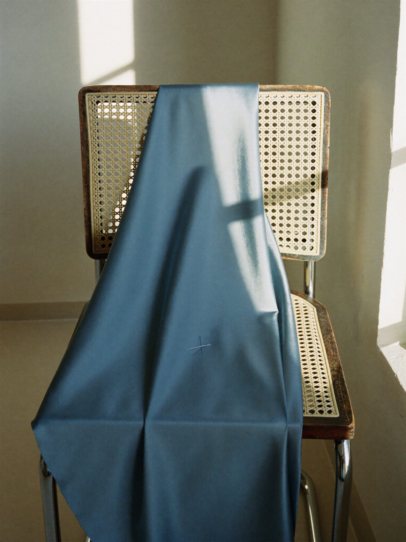 Bolt of ocean-blue silk draped over a cane chair